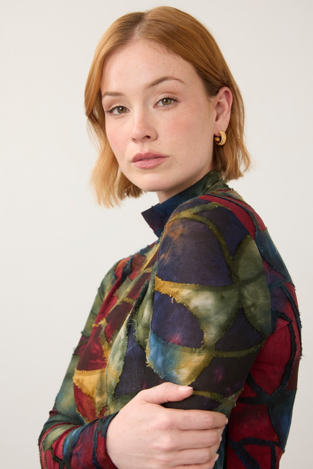 Broderick's Clothing Co. FDJ long sleeve mock neck top with a bold, multi-colored geometric print on a woman.