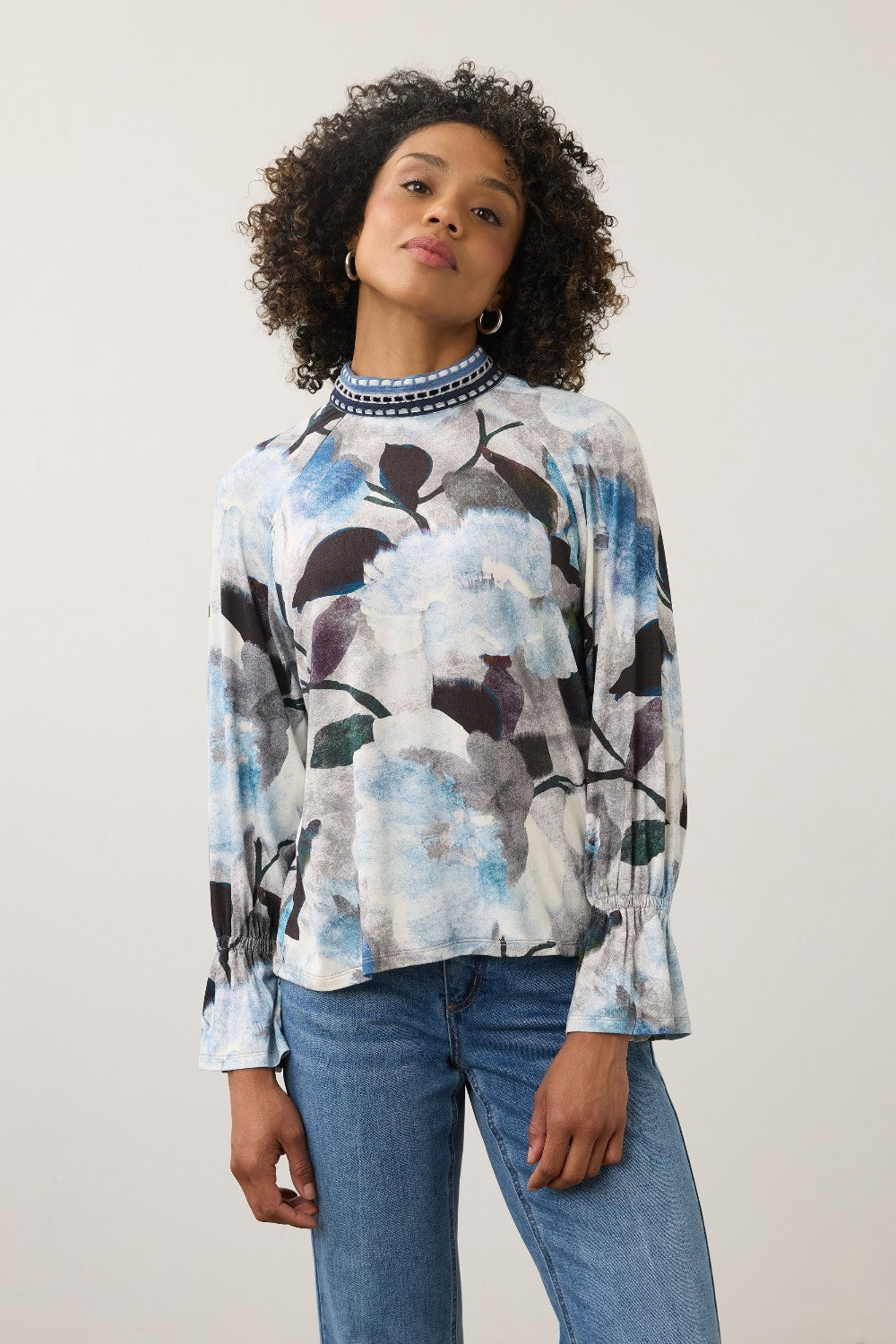 Model wearing Broderick's Clothing Co. FDJ floral print long sleeve top with a blue patterned high neck and cuffs.