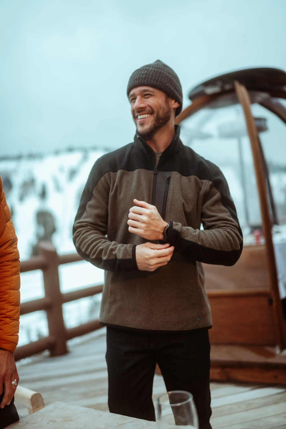 Broderick's Clothing Co. KÜHL SKORCHR fleece quarter-zip sweater in olive and black worn by a man in a snowy setting.