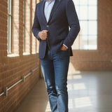 Broderick's Clothing Co. navy denim knit sport coat worn by a man in a light blue shirt and jeans in a loft space.