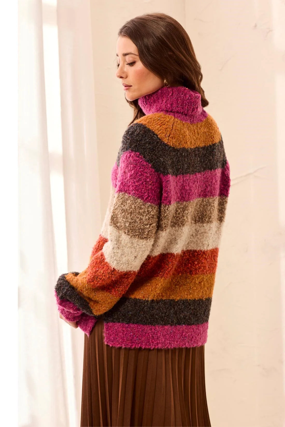 Broderick's Clothing Co. multi-colored striped bouclé turtleneck sweater with a relaxed fit on a female model.