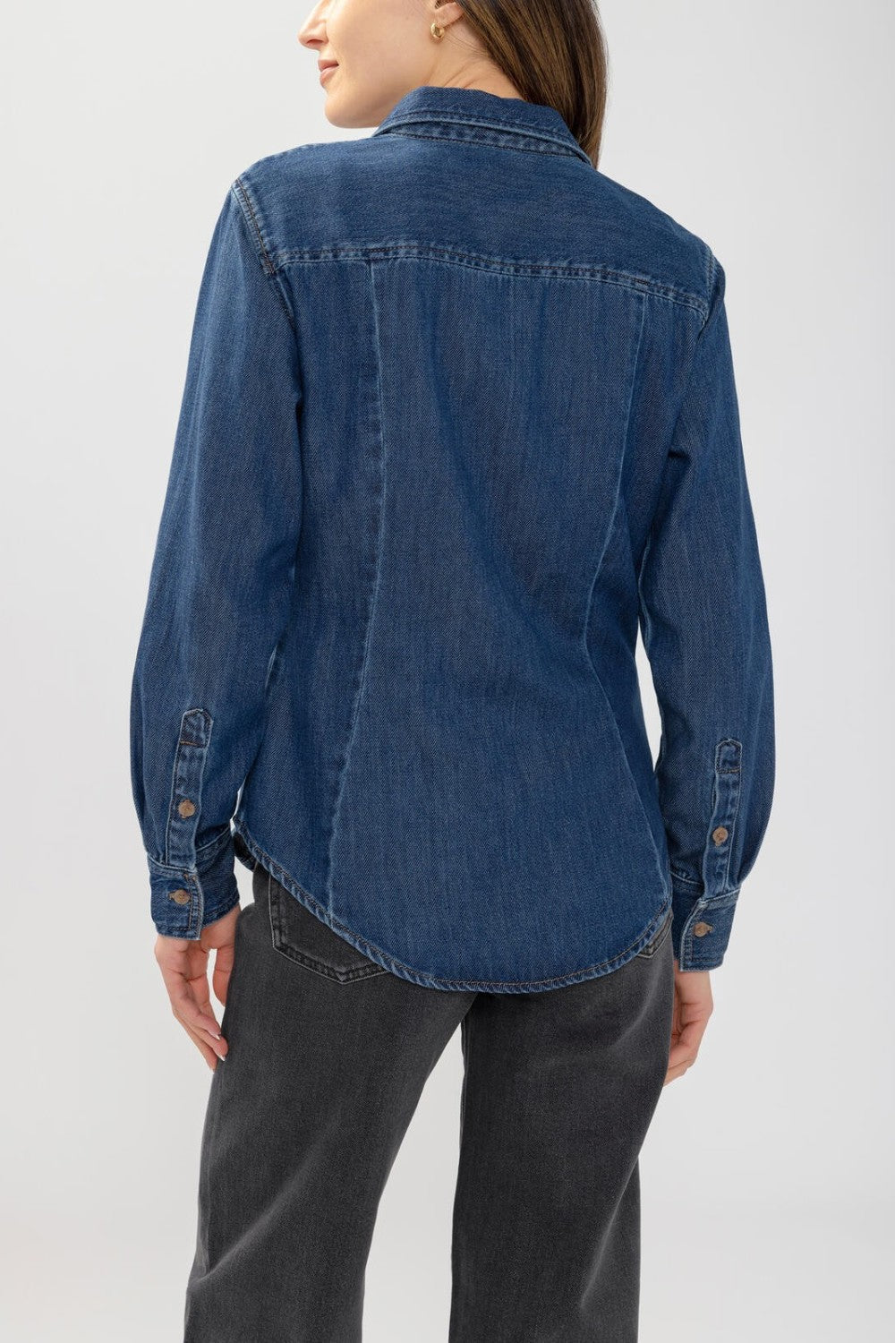 Back view of a woman wearing a Broderick's Clothing Co. medium-wash blue denim shirt with princess seams.