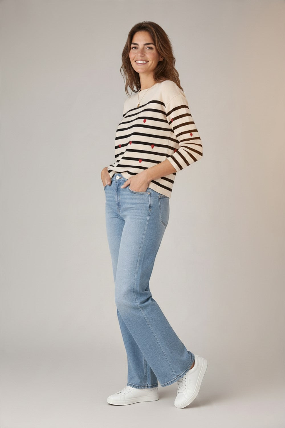 Broderick's Clothing Co. apricot striped crew neck sweater with red embroidered hearts worn with light wash jeans.