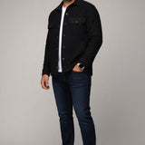 Model wearing a black Broderick's Clothing Co. Au Noir GRADO overshirt over a white t-shirt and dark blue jeans.