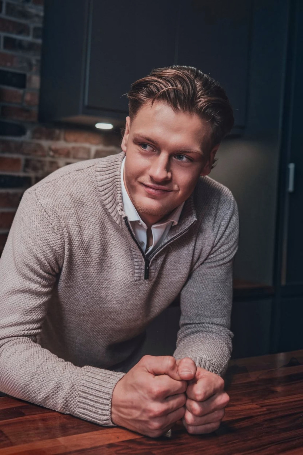 Broderick's Clothing Co. Au Noir VOGAR beige merino wool blend quarter zip sweater worn by a man in a kitchen.