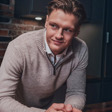 Broderick's Clothing Co. Au Noir VOGAR beige merino wool blend quarter zip sweater worn by a man in a kitchen.