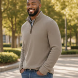 Broderick's Clothing Co. man wearing a beige melange quarter-zip sweater over a plaid shirt and blue jeans outdoors.