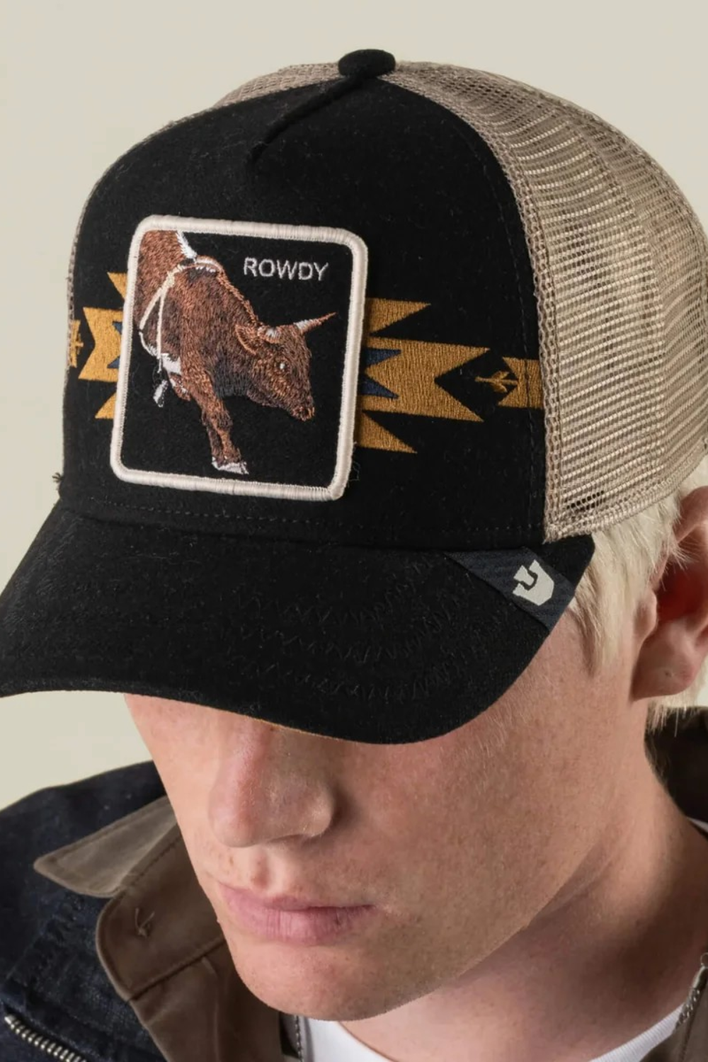 Broderick's Clothing Co. Goorin Bros. black trucker hat with a bull patch and tan mesh back worn by a man.