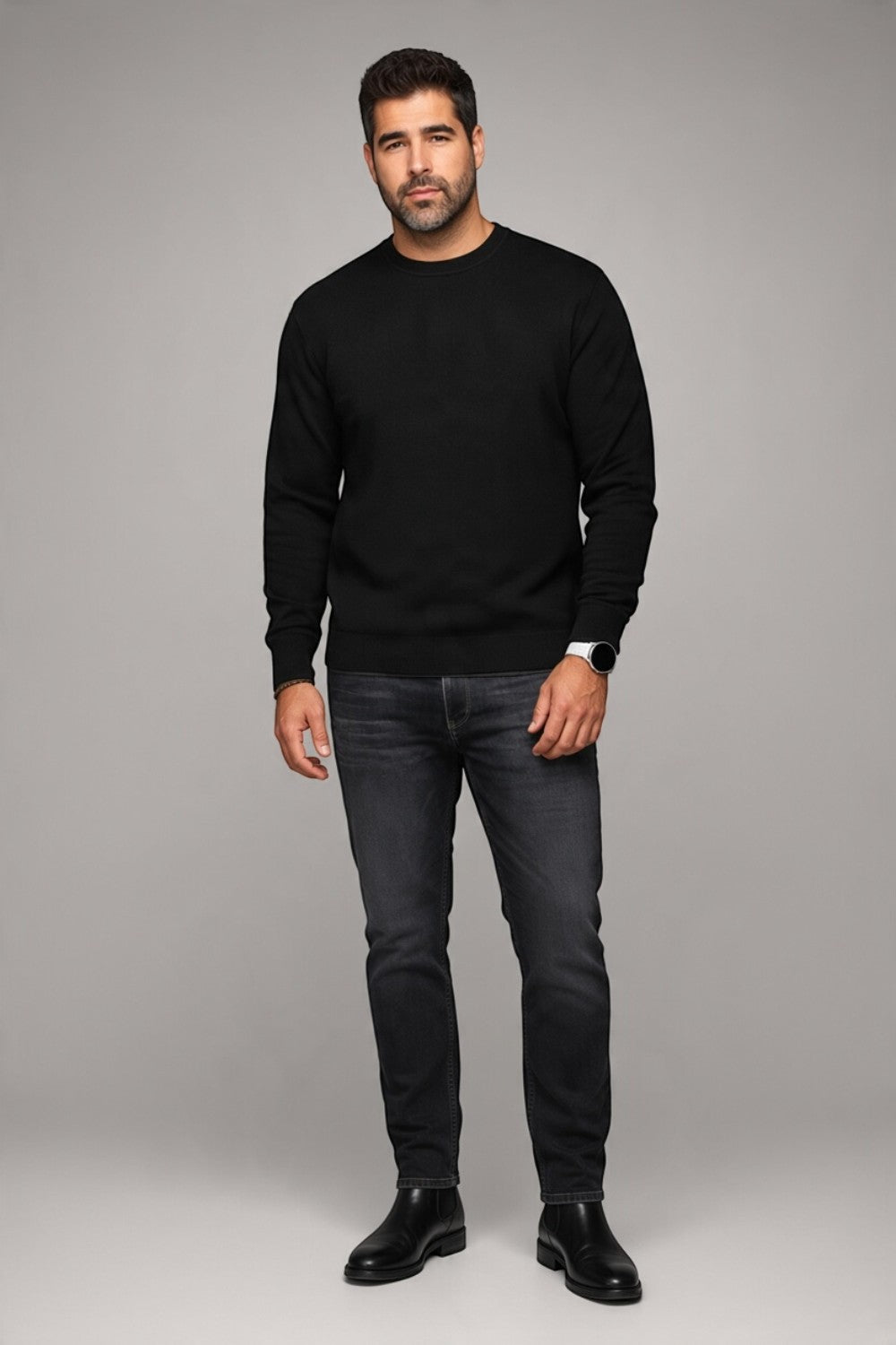 A man wearing a black Broderick's Clothing Co. Au Noir LACAUNE cashmere sweater with dark jeans and black boots.