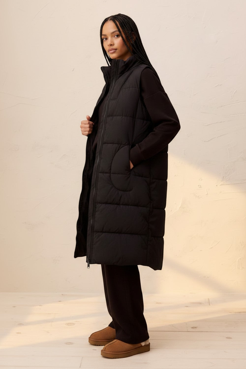 Model wearing a Broderick's Clothing Co. black longline quilted vest with a zip-front closure and side pockets.