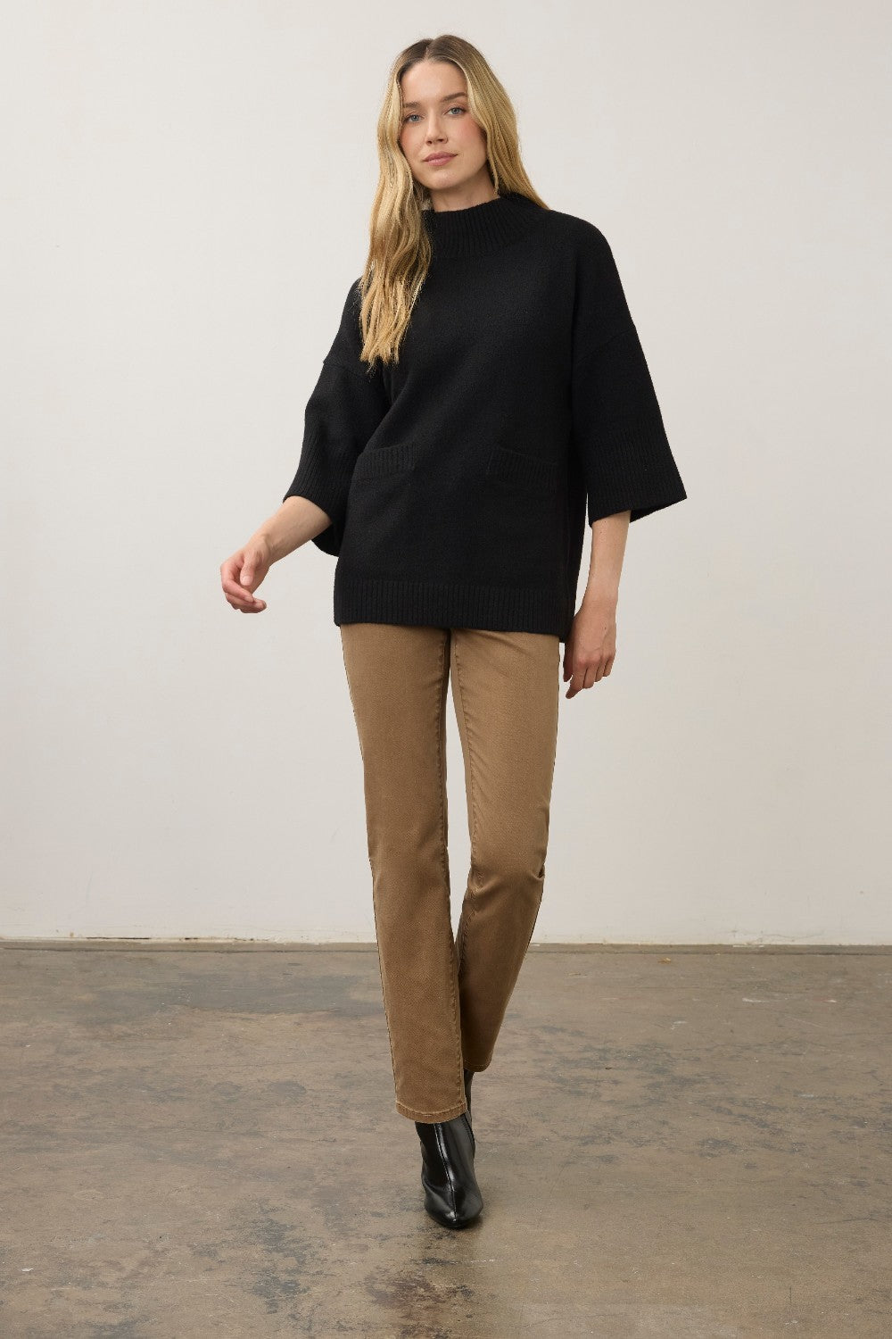 Broderick's Clothing Co. black mock neck sweater with 3/4 sleeves and a relaxed fit worn with tan trousers