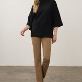 Broderick's Clothing Co. black mock neck sweater with 3/4 sleeves and a relaxed fit worn with tan trousers