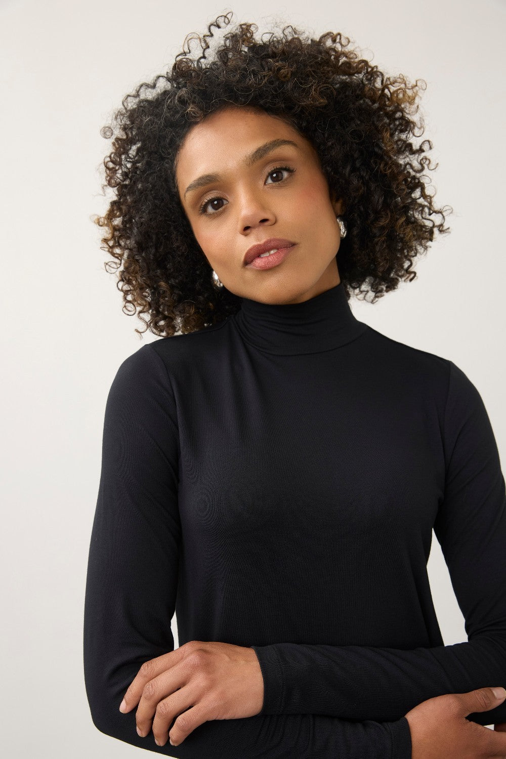 Model wearing a black Broderick's Clothing Co. long sleeve mock neck top with a fitted silhouette