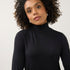 Model wearing a black Broderick's Clothing Co. long sleeve mock neck top with a fitted silhouette