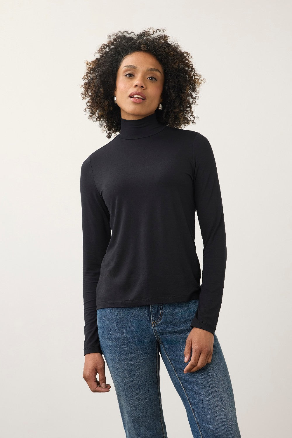 Model wearing a Broderick's Clothing Co. black long sleeve mock neck top paired with blue jeans.