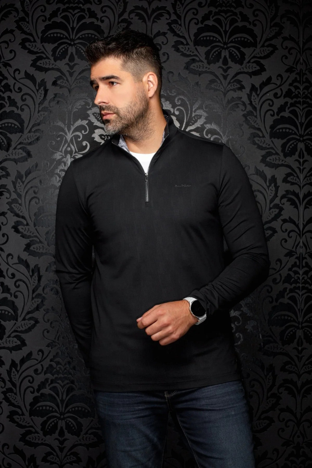 Broderick's Clothing Co. Au Noir BONNEFOI black quarter-zip sports sweater worn by a man against a damask background.