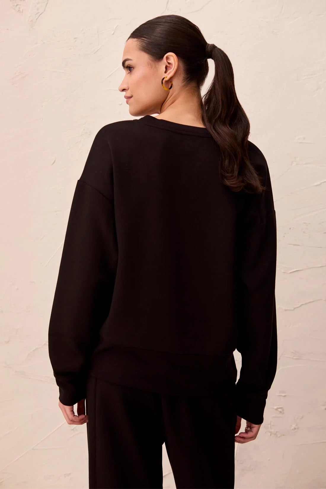 Broderick's Clothing Co. black Techno Lux scuba knit pullover with drop shoulders and ribbed hem, back view.