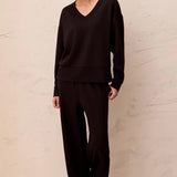 Model wearing Broderick's Clothing Co. black V-neck drop shoulder pullover in smooth techno lux scuba knit fabric.