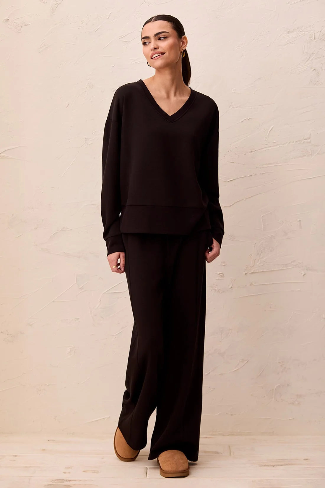 Broderick's Clothing Co. black V-neck pullover with drop shoulders in technical scuba knit worn with matching pants.