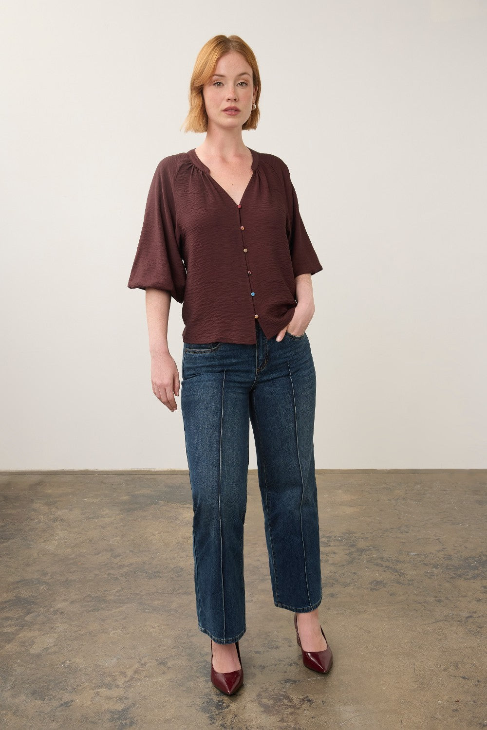 Broderick's Clothing Co. dark brown 3/4 sleeve blouse with colourful buttons worn by a woman with blue jeans