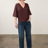 Broderick's Clothing Co. dark brown 3/4 sleeve blouse with colourful buttons worn by a woman with blue jeans