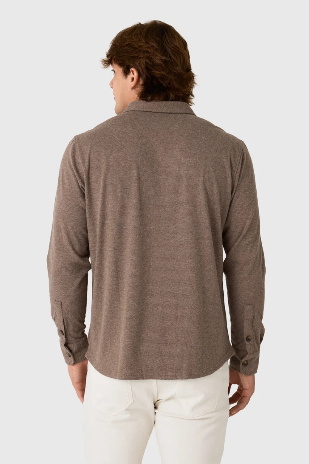 Back view of a man wearing a Broderick's Clothing Co. brown twill overshirt with long sleeves and buttoned cuffs.