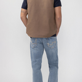 Broderick's Clothing Co. brown taupe workwear vest worn over a dark t-shirt and blue jeans, back view.