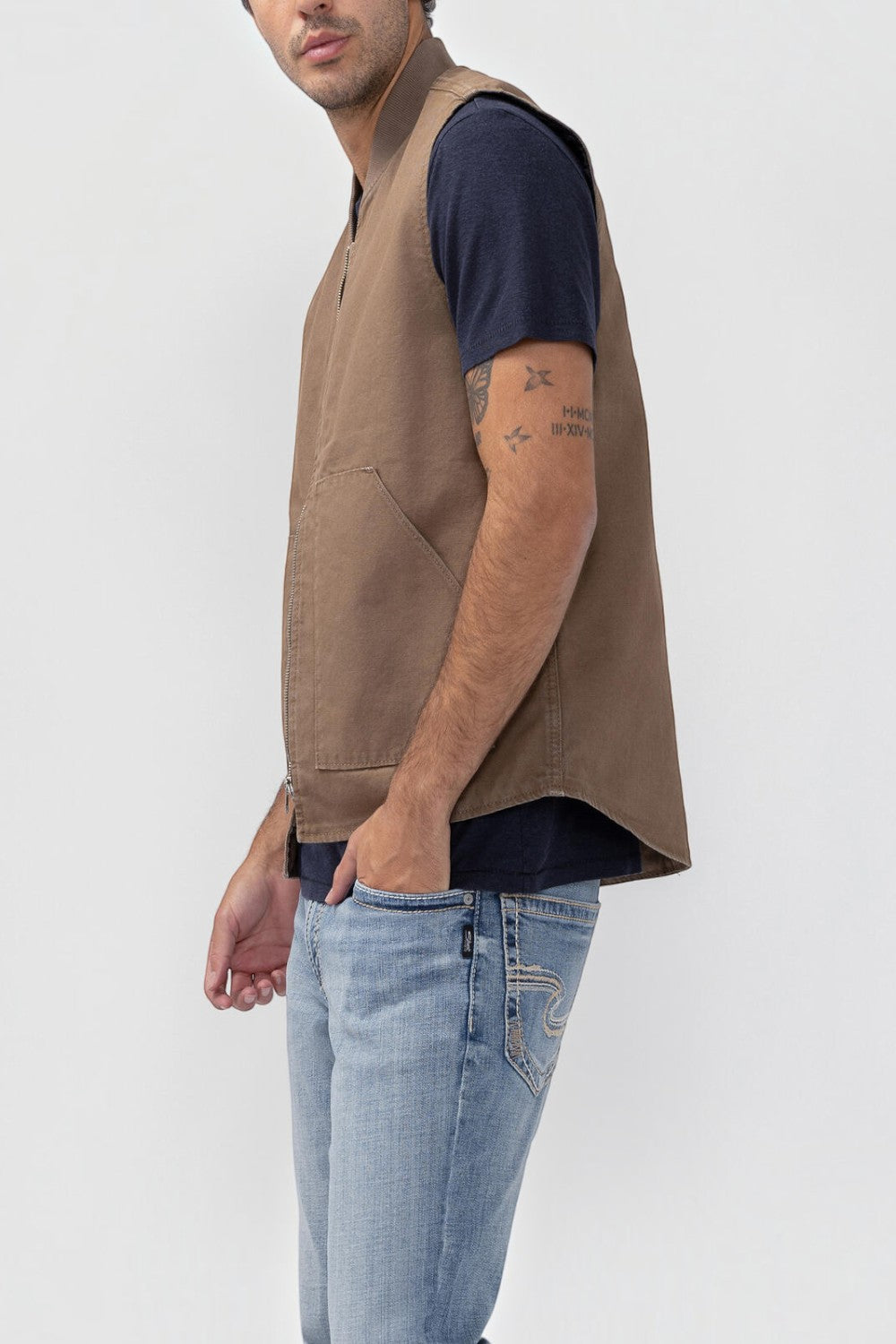 Broderick's Clothing Co. brown taupe workwear vest with a zip front and patch pockets worn by a man in a t-shirt