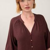 Broderick's Clothing Co. burgundy 3/4 sleeve blouse with colourful buttons and a V-neckline worn by a woman