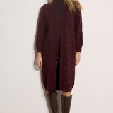Broderick's Clothing Co. burgundy cable knit midi cardigan worn by a model with brown boots against a white wall.