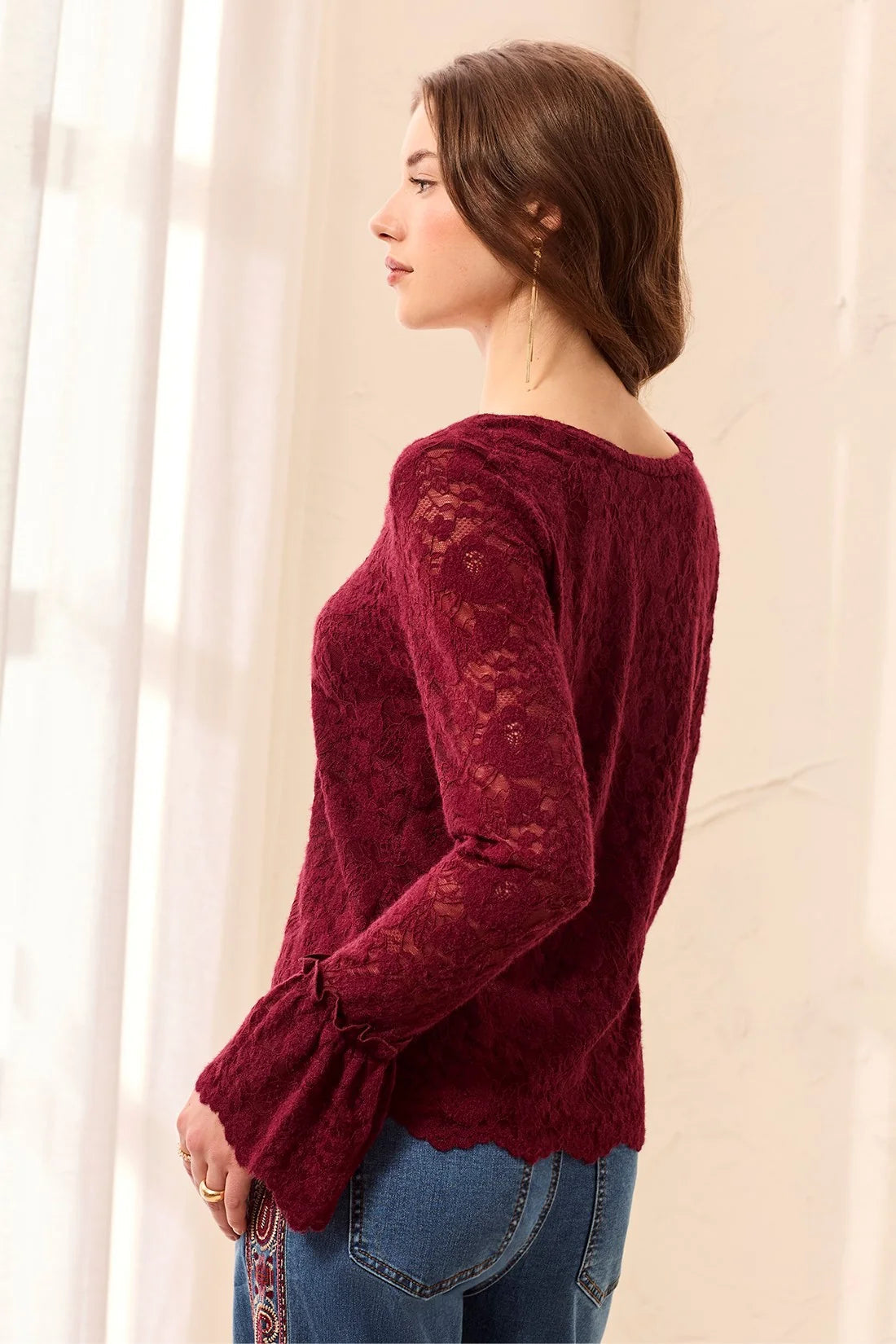 Broderick's Clothing Co. burgundy lace top with long flared sleeves and scalloped hem worn with blue jeans