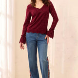 Broderick's Clothing Co. burgundy lace top with V-neck, scalloped hem, and flared cuffs worn with patterned jeans.