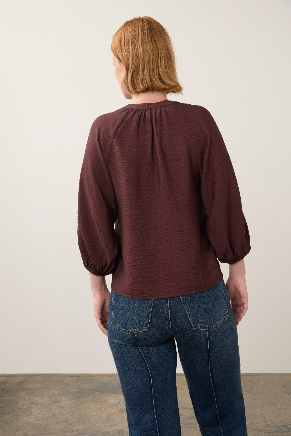 Back view of a woman wearing a Broderick's Clothing Co. burgundy 3/4 sleeve shirt with a textured fabric finish.