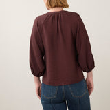 Back view of a woman wearing a Broderick's Clothing Co. burgundy 3/4 sleeve shirt with a textured fabric finish.