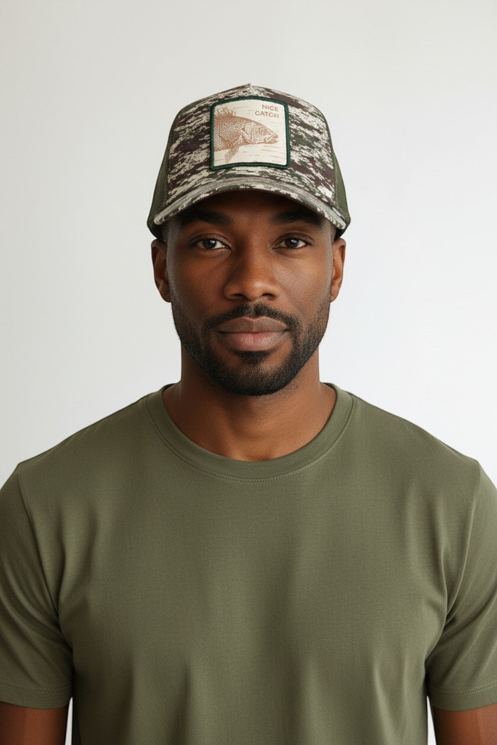 Broderick's Clothing Co. Goorin Bros. camo trucker hat with engraved bass patch worn by a man in an olive t-shirt.