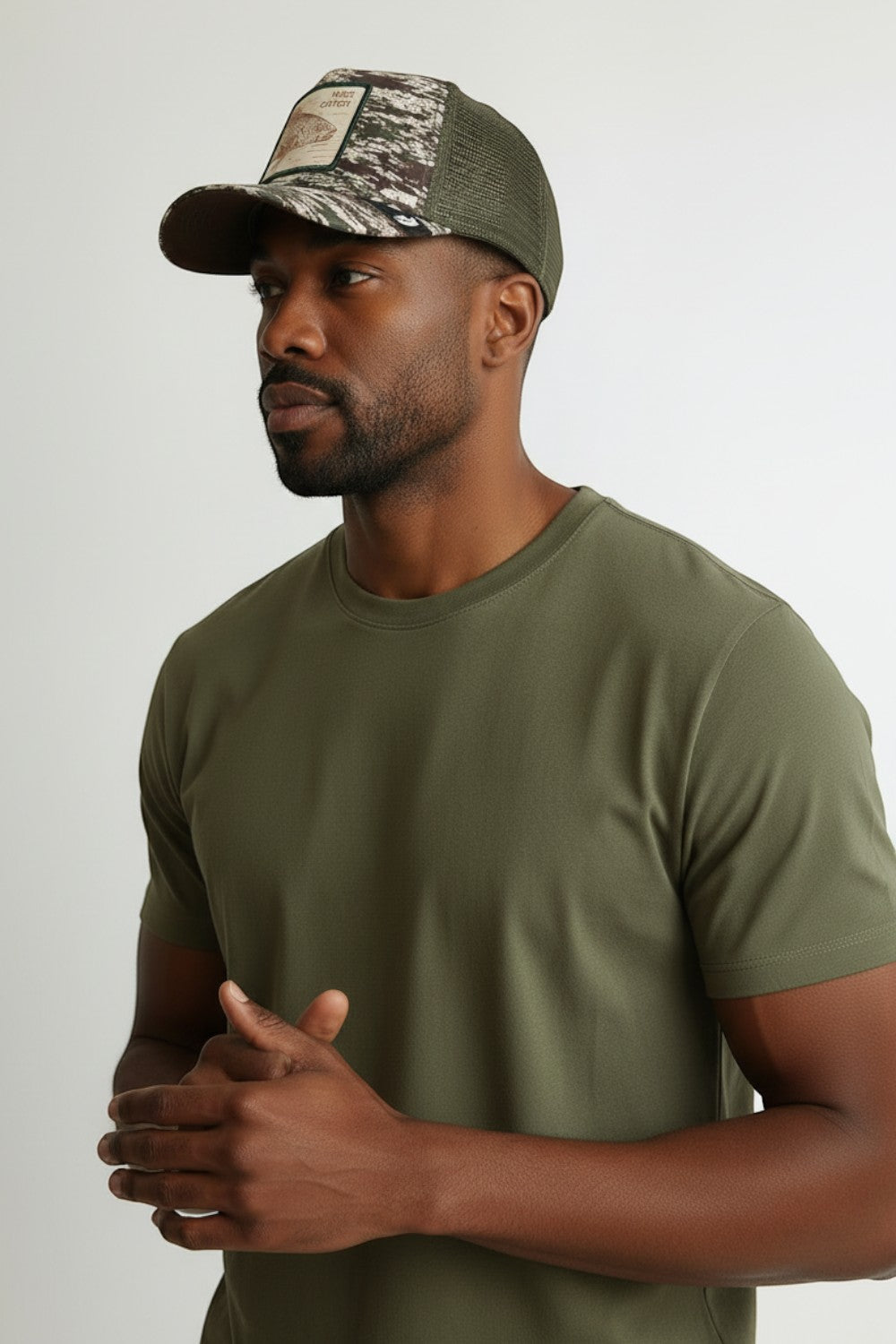 Broderick's Clothing Co. Goorin Bros. camouflage trucker hat with engraved bass patch worn by a man in an olive tee.