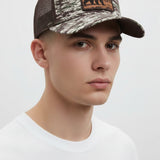 Broderick's Clothing Co. Goorin Bros. camo trucker hat with an engraved bear patch on a model against a white background