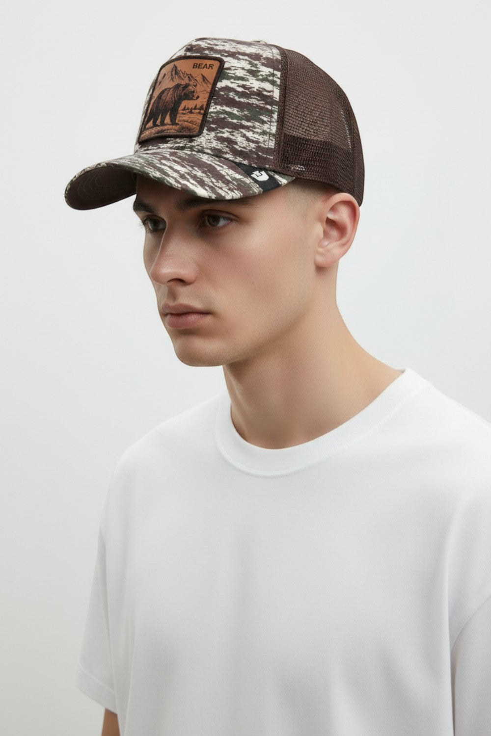 Broderick's Clothing Co. Goorin Bros. camo trucker hat with brown mesh back and engraved bear patch on a male model.