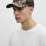 Broderick's Clothing Co. Goorin Bros. camo trucker hat with brown mesh back and engraved bear patch on a male model.