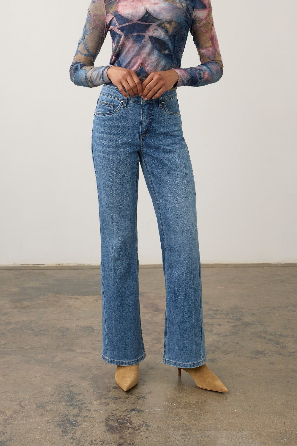 Model wearing Broderick's Clothing Co. FDJ Olivia medium blue denim bootcut jeans with knee panel detail.
