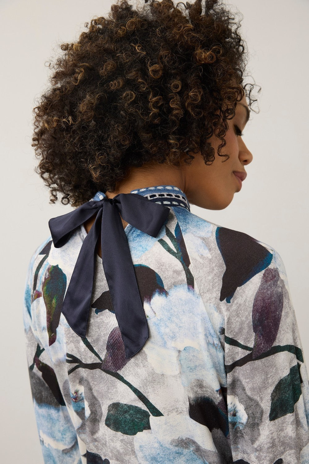 Broderick's Clothing Co. FDJ top featuring a blue and grey floral print with a sophisticated navy bow back neckline.