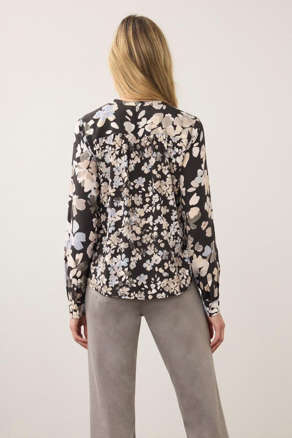 Back view of a woman wearing a Broderick's Clothing Co. FDJ long sleeve blouse with a black floral print pattern.