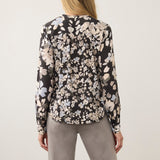 Back view of a woman wearing a Broderick's Clothing Co. FDJ long sleeve blouse with a black floral print pattern.