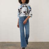 Model wearing Broderick's Clothing Co. FDJ floral print top with a high neck and blue denim flared jeans