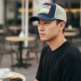 Man wearing a navy and beige Goorin Bros. LIVIN' THE DREAM trucker hat from Broderick's Clothing Co. at a cafe table.
