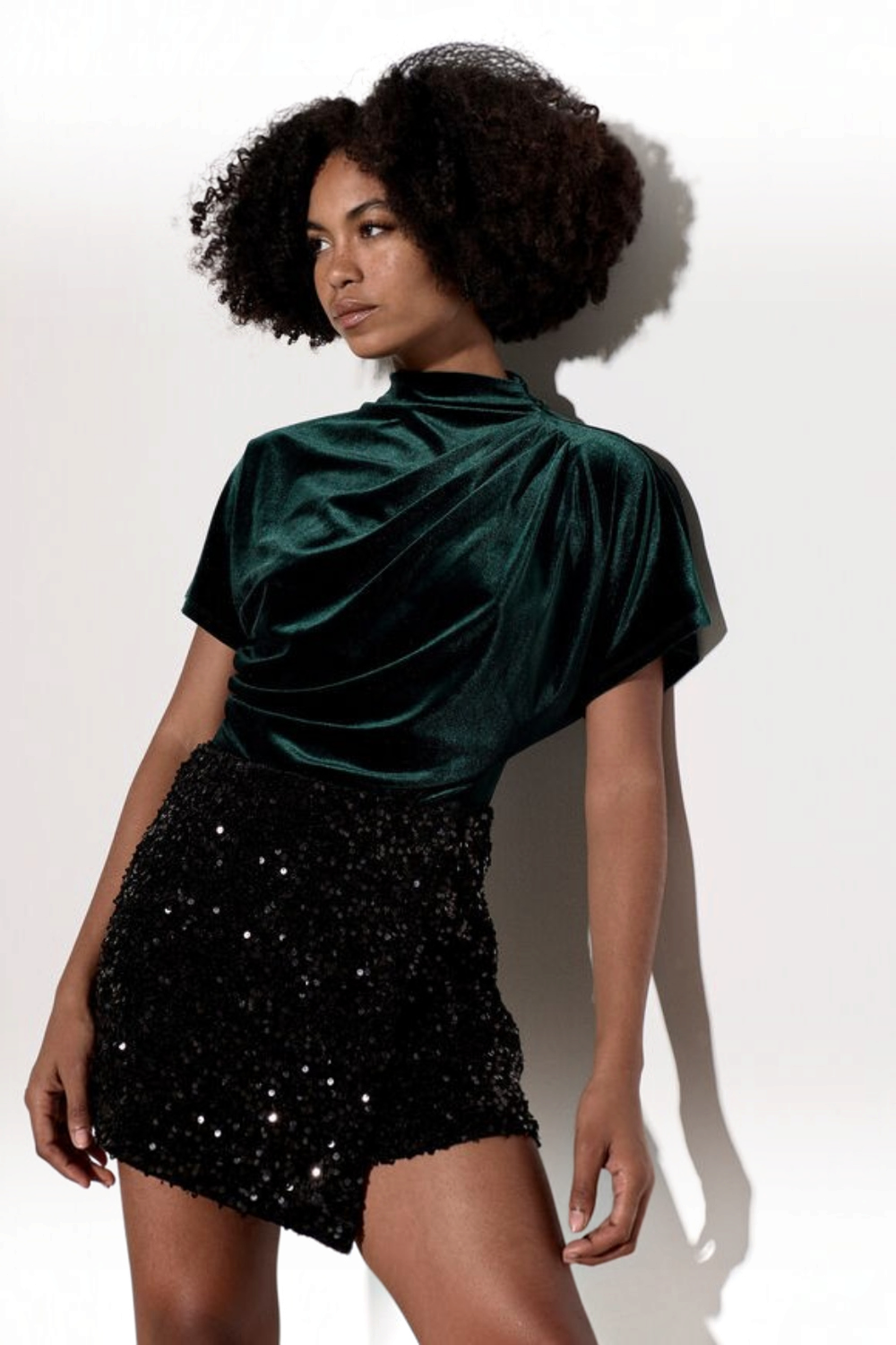 Broderick's Clothing Co. dark green velvet top with a high cowl neck and pleated detail worn by a model.