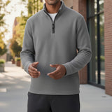 Man wearing a Broderick's Clothing Co. grey melange quarter-zip sweater with textured fabric in an outdoor setting.