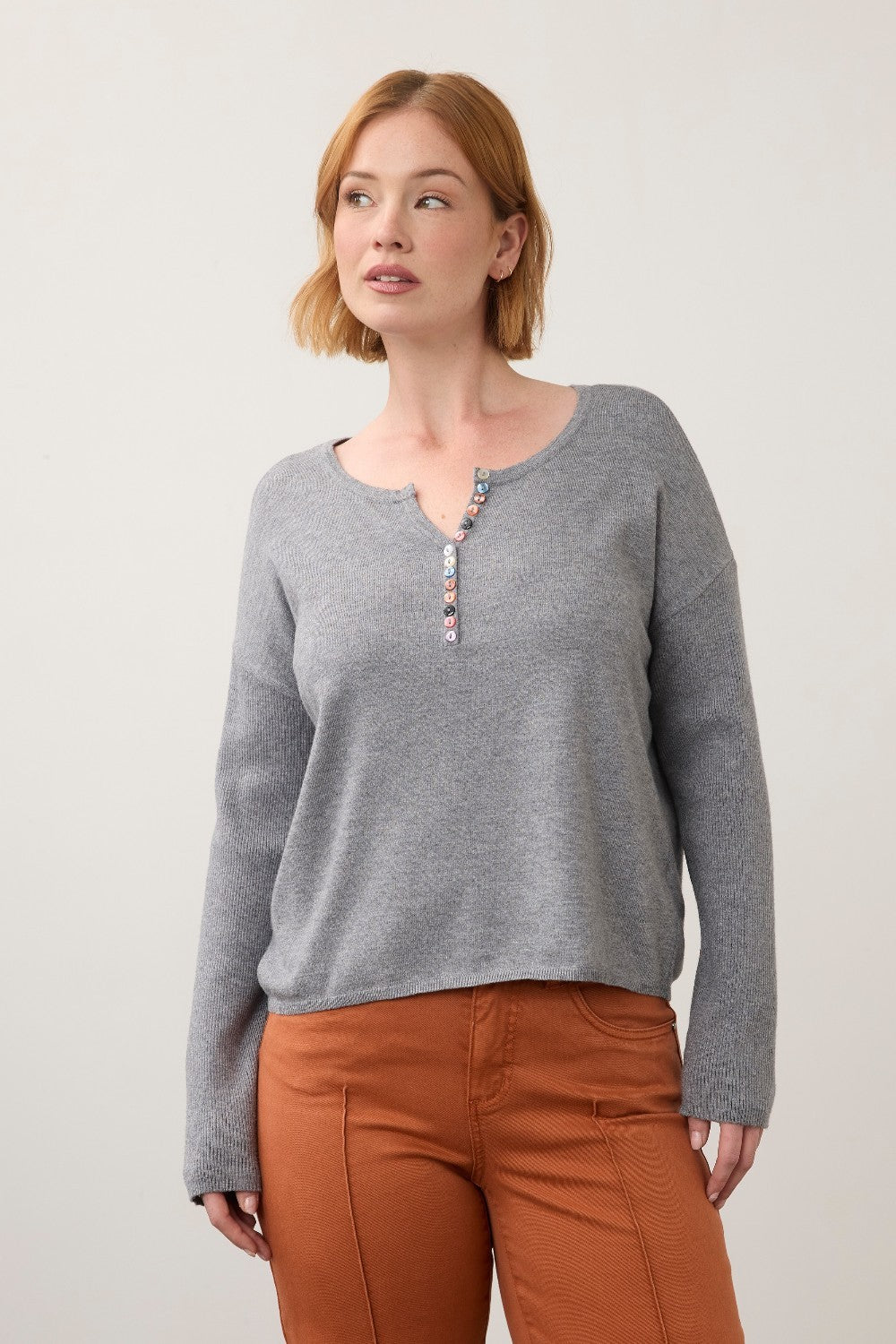 Broderick's Clothing Co. grey notch neck sweater with ribbed sleeves and colourful button detail on a female model