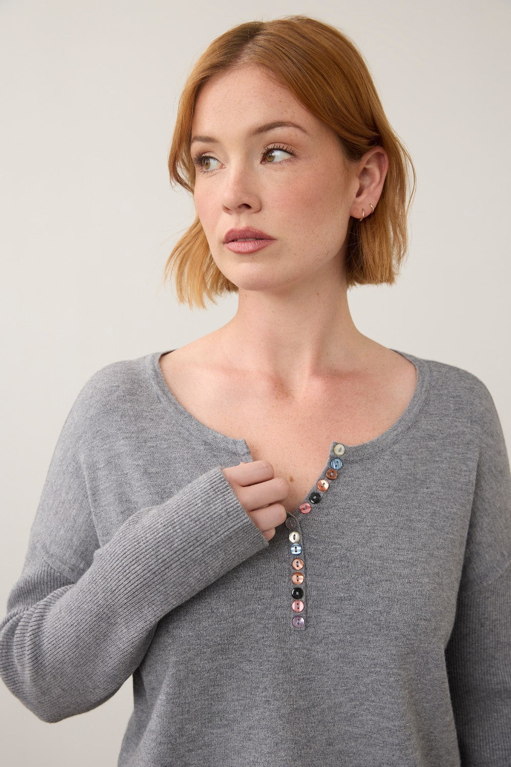 Broderick's Clothing Co. grey notch neck sweater with ribbed sleeves and colourful button detail on a woman