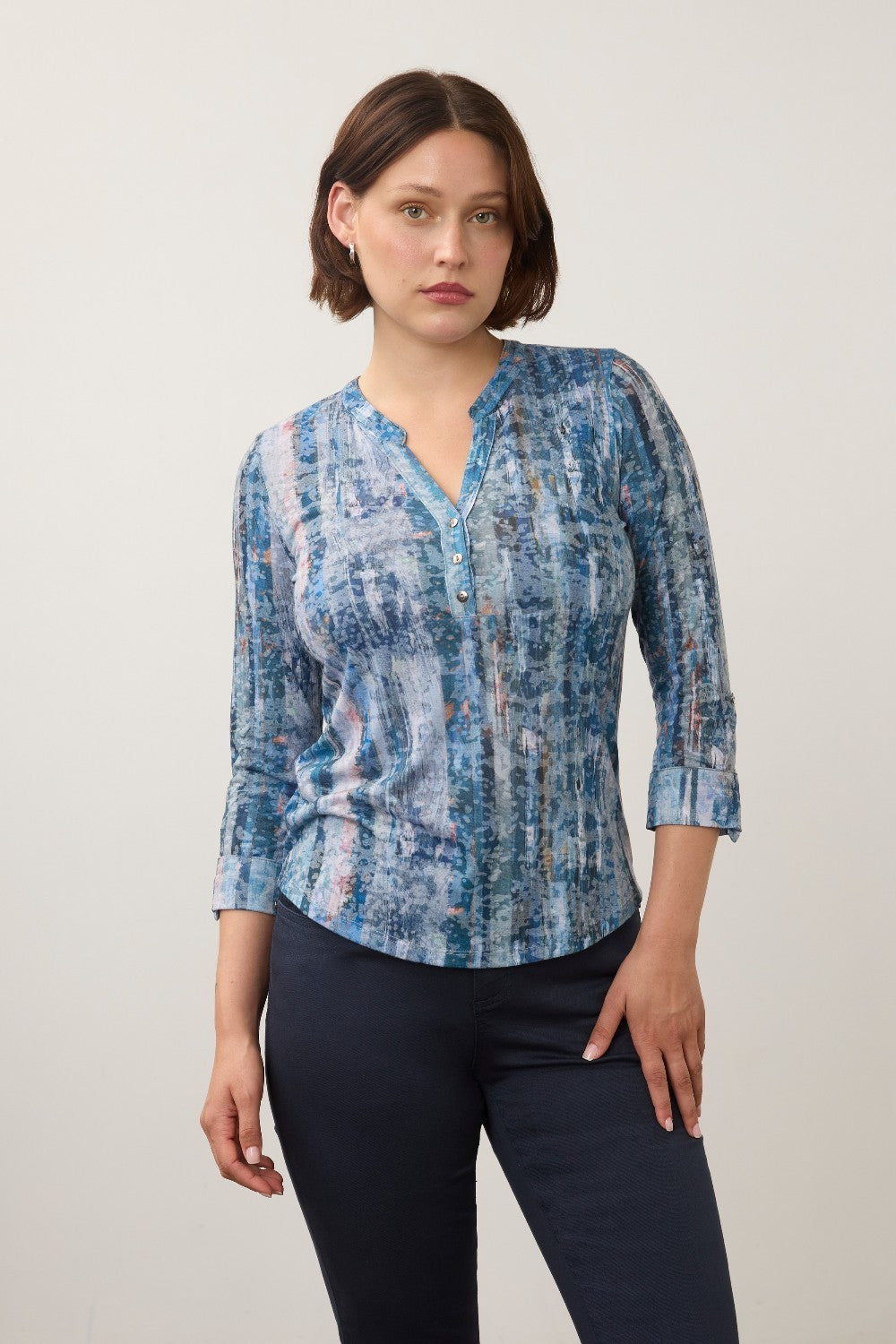 Woman wearing a printed blue top with blue pants on a light back ground.